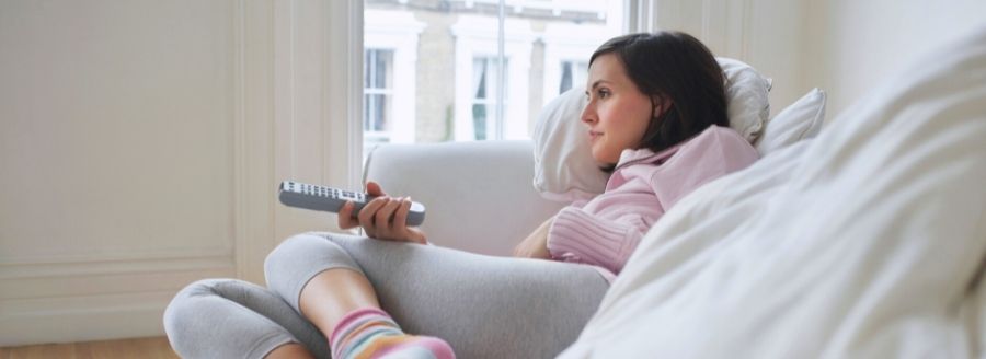 Quoi faire quand on est seul à la Saint-Valentin - Femme qui s'ennuie, regarde la télévision - Blogue | Clinique de Psychologie Québec