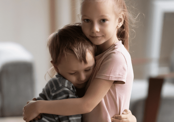 Un frère et une soeur en bas âge qui s'enlacent - Le deuil durant l'enfance - Blogue | Clinique de Psychologie Québec