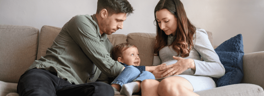 Famille avec un bambin qui caresse le ventre de la femme enceinte