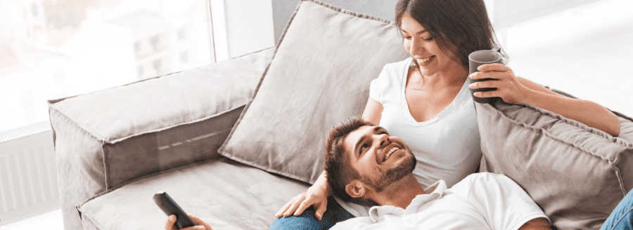 Couple souriant, la tête de l'homme sur les jambes de la femme - L’arrivée d’un enfant et les difficultés pour le couple! - Blogue | Clinique de Psychologie Québec