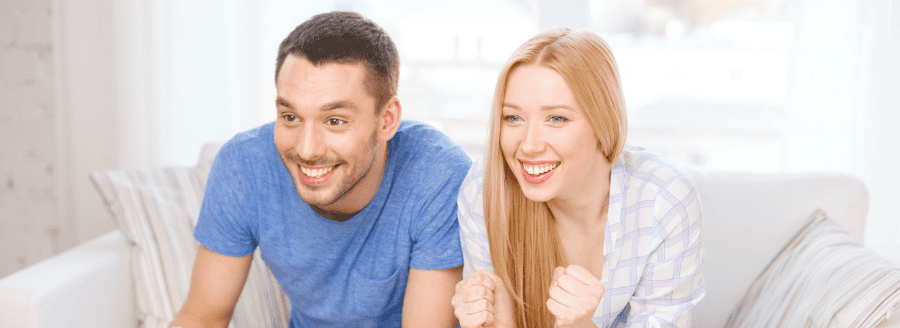 Couple regardant du sport à la télévision avec enthousiasme - L’arrivée d’un enfant et les difficultés pour le couple! - Blogue | Clinique de Psychologie Québec