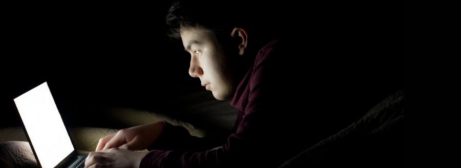 Garçon qui regarde son ordinateur portable en pleine nuit - L'impact d'Internet et des médias sociaux dans le développement de la sexualité chez les adolescents - Blogue | Clinique de Psychologie Québec