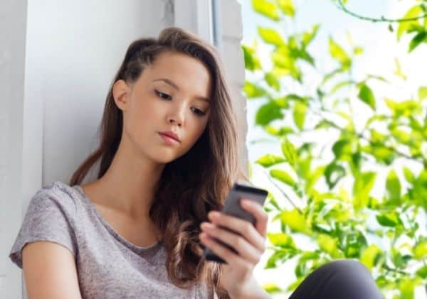 Adolescente blasée qui regarde son téléphone cellulaire - L'impact d'Internet et des médias sociaux dans le développement de la sexualité chez les adolescents - Blogue | Clinique de Psychologie Québec